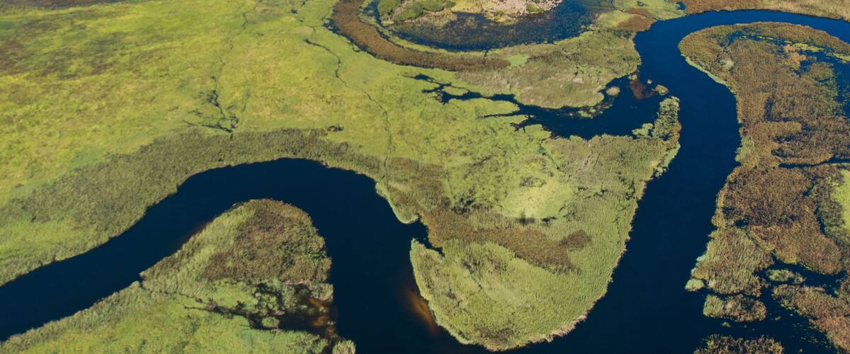 A river meandering through a green landscape with several small islands and a large central island.