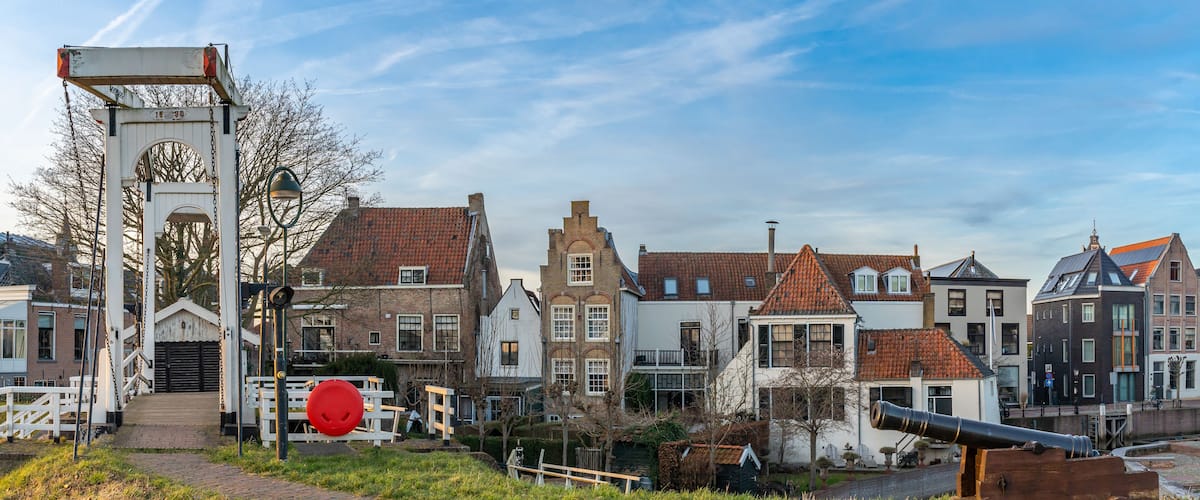 A historic town with traditional architecture, a bridge, and a cannon.