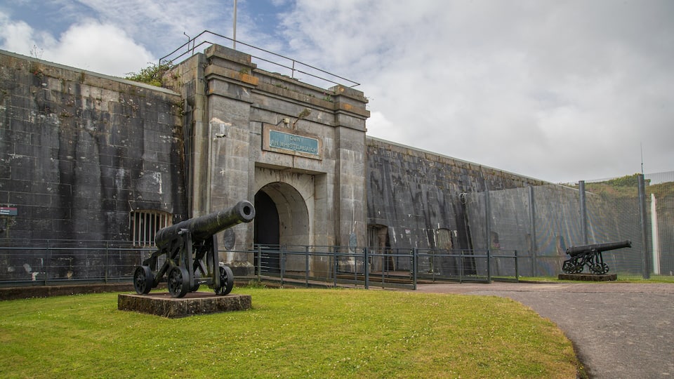 A historic fort with cannons, a large arched entrance, and a plaque reading "Dun Can Local Whistelaigh".