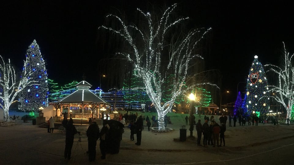 A snow-covered plaza with illuminated trees and a gazebo.