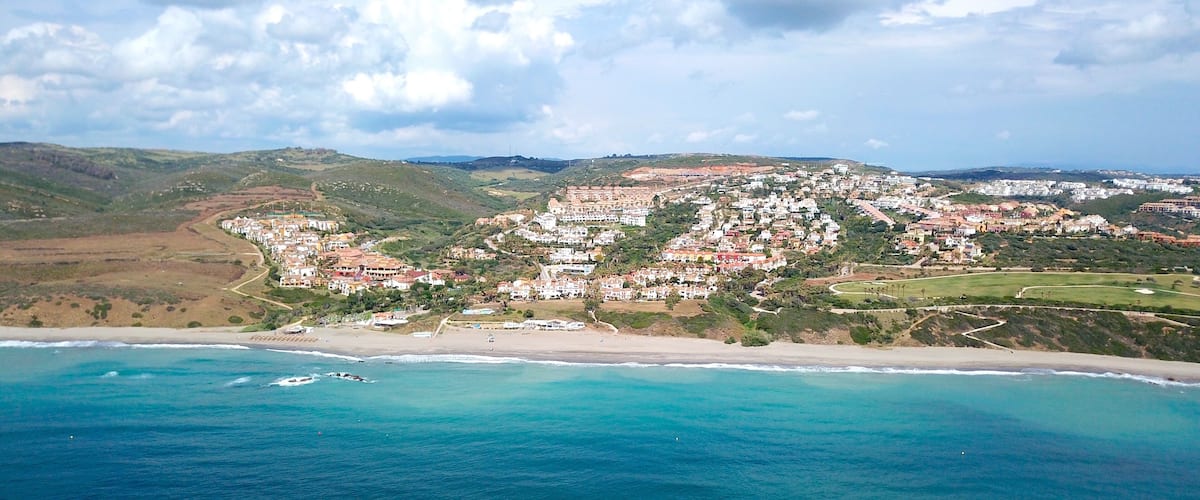 A coastal town with a beach, houses, and hills.