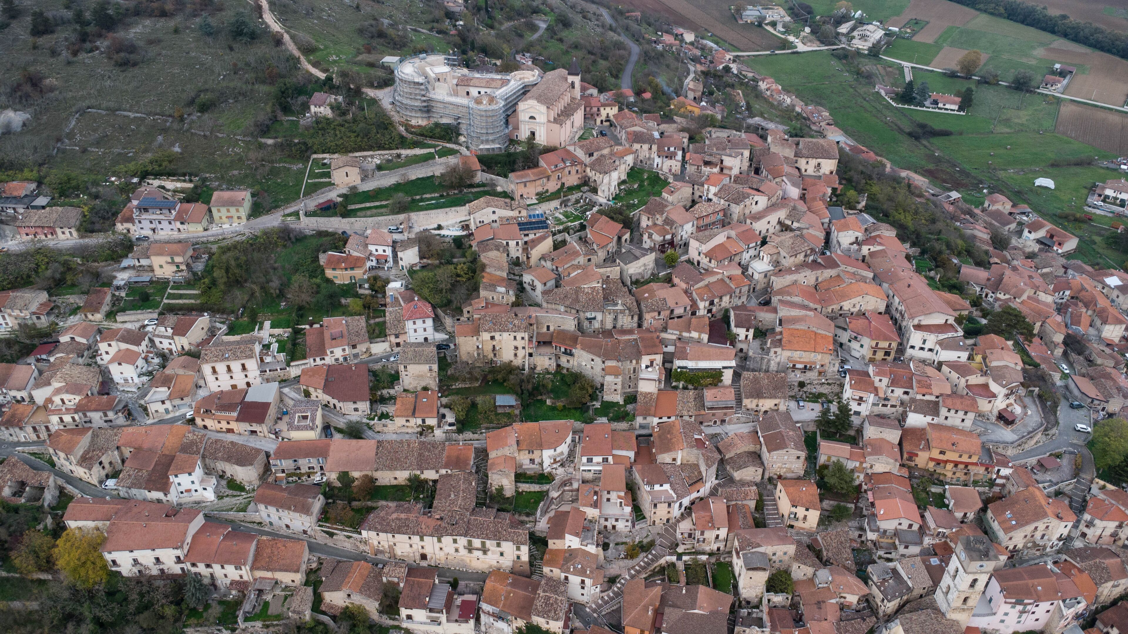 An aerial view of a historic town with tightly packed buildings, a prominent church, and surrounding fields.