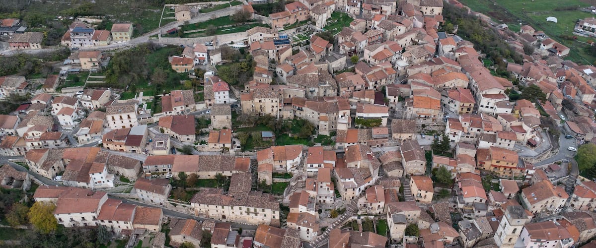 An aerial view of a historic town with tightly packed buildings, a prominent church, and surrounding fields.