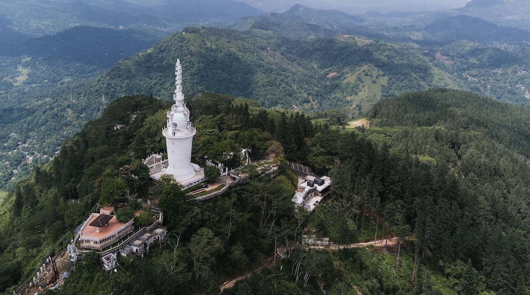 Aerial view of the white Ambuluwawa Tower located on a mountain peak surrounded by lush greenery, in Kandy, Sri Lanka