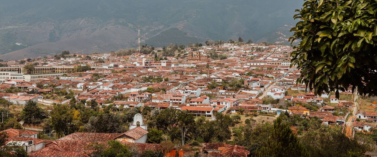 A town with red-tiled roofs, surrounded by hills and greenery.