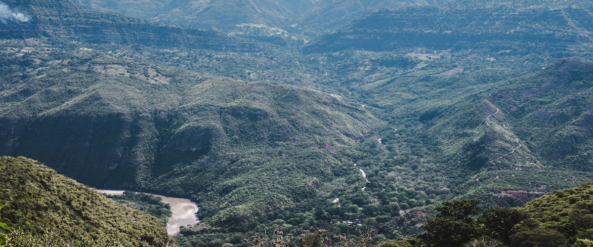 A mountainous landscape with dense forests and a winding river.