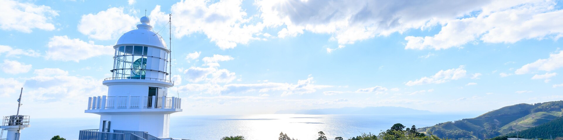 Un faro con una vista despejada del mar y colinas al fondo.