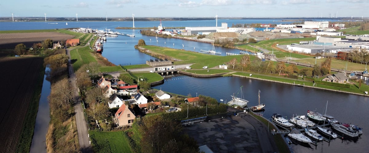 A river with boats, wind turbines, and industrial buildings.