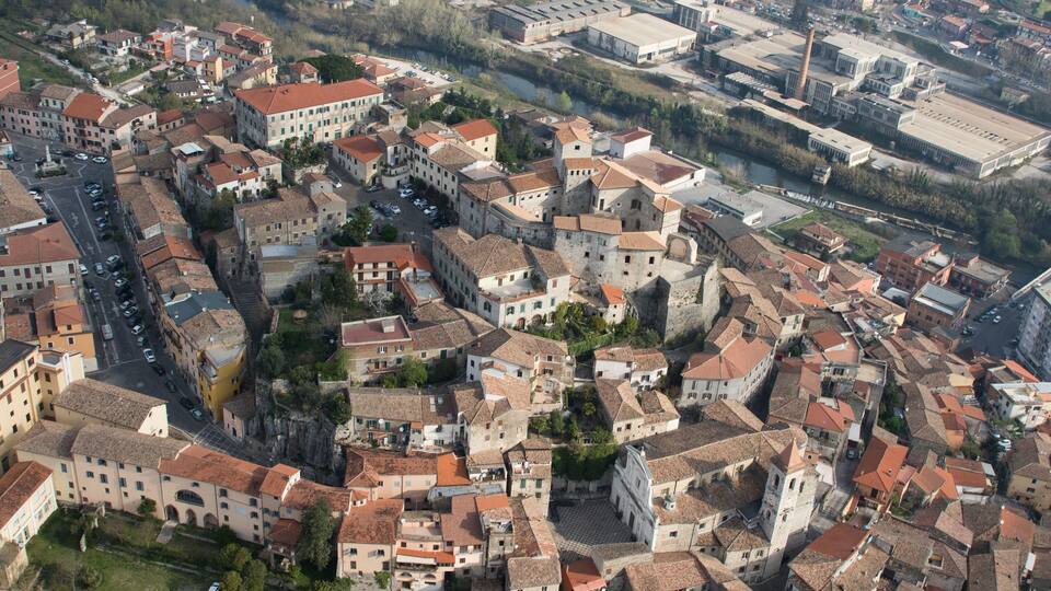 An aerial view of a historic town with tightly packed buildings, narrow streets, and a prominent church tower.
