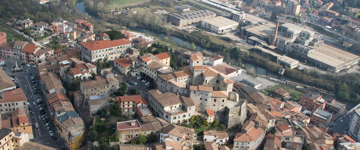 An aerial view of a historic town with tightly packed buildings, narrow streets, and a prominent church tower.