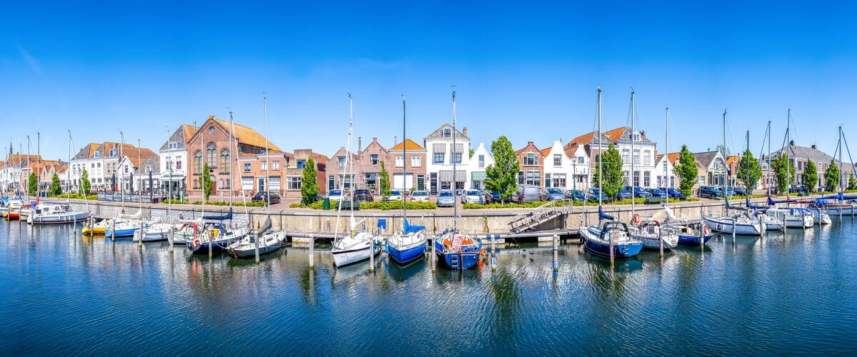 A marina with boats docked along a waterfront, surrounded by historic buildings.
