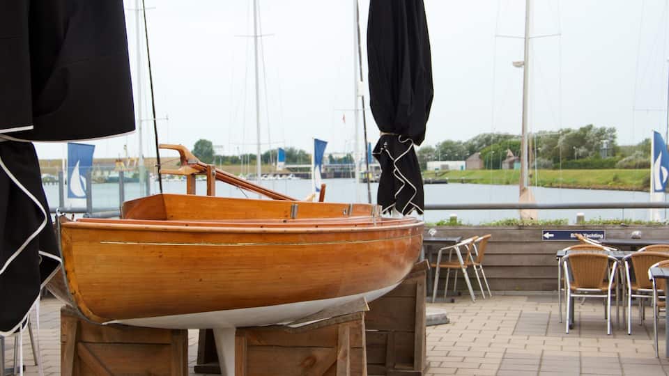 A wooden boat on display, a waterfront view, and outdoor seating area.