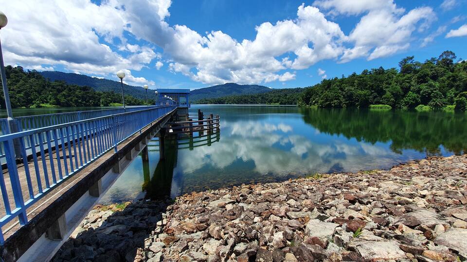 A calm lake with a blue bridge and rocky shore.