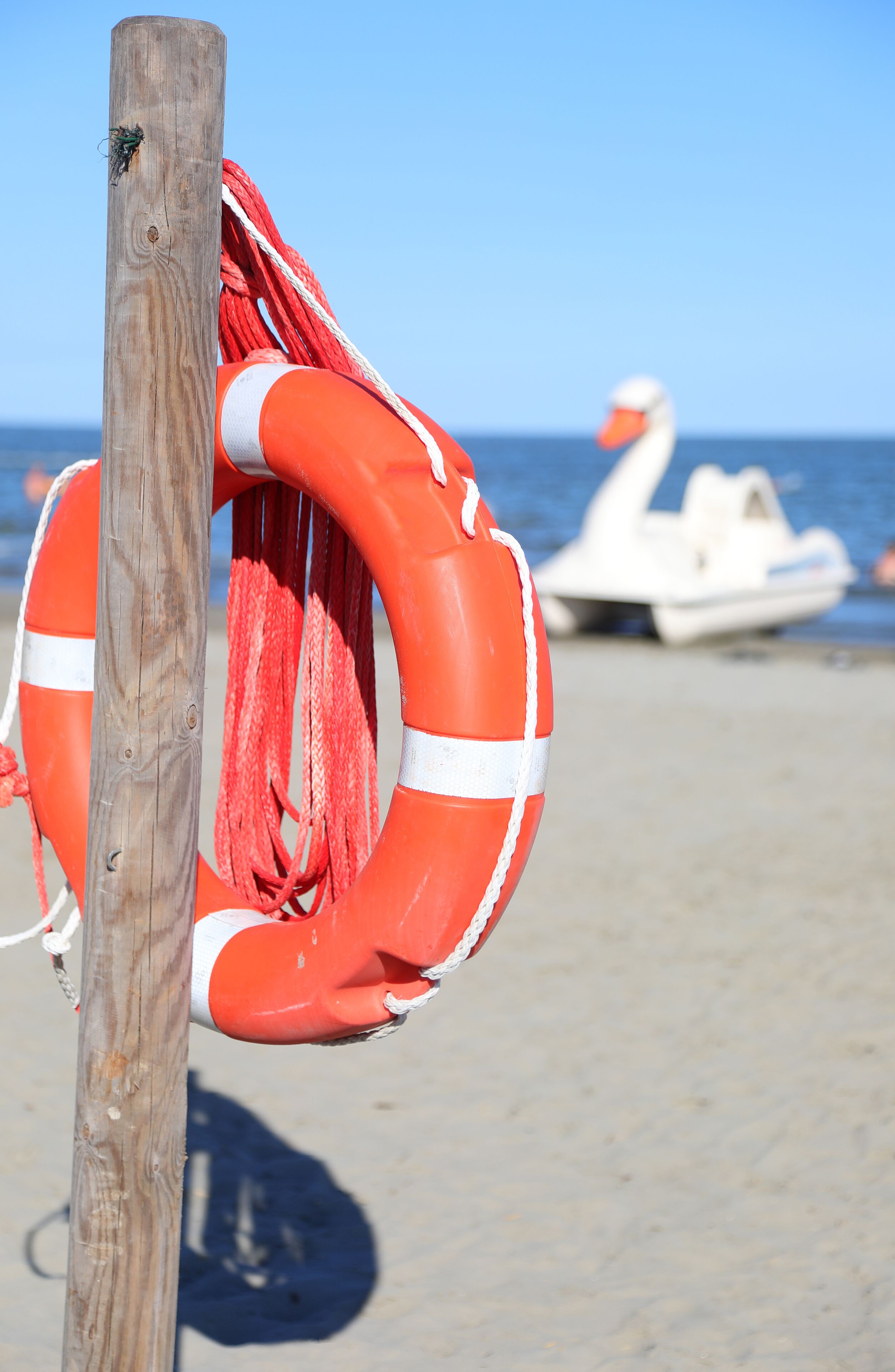 life preserver hanging on the pole on the sandy beach to assist lifeguards during drownings at sea