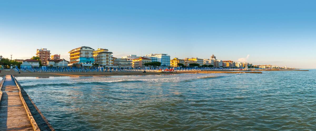 A coastal cityscape with a pier extending into the sea, colorful buildings, and a clear sky.