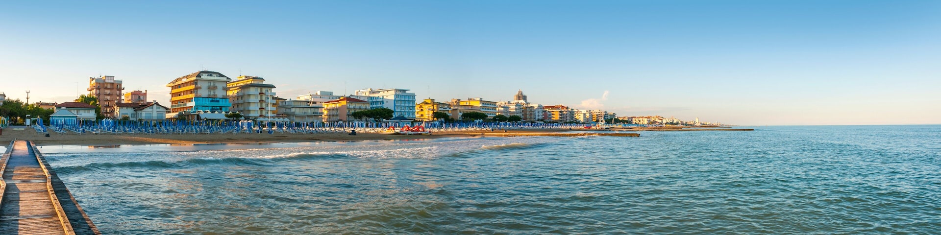 A coastal cityscape with a pier extending into the sea, colorful buildings, and a clear sky.