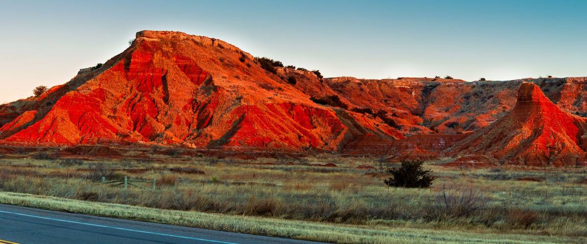 A red rock formation with a road in the foreground.