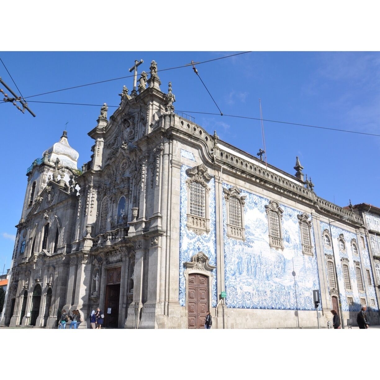 I thought this was just one church, but it is actually two connected by one of the world's narrowest houses - just 1 metre wide. 

To the left is Carmelitas Church, part of a former 17th century convent with a simple classical façade, a bell tower, and a richly gilded interior. 

To the right is Carmo Church, built later in the 18th century. It is a magnificent example of late baroque architecture with a single nave made up of elegant gilt carvings in seven altars by master Francisco Pereira Campanhã. 
Outside, an extraordinary side wall is completely covered in blue and white tile panels. 

The house that separates the two churches was inhabited until about 20 years ago. It was built due to a law that stated that no two churches could share a wall, while also ensuring chastity between the monks of Carmo and the nuns of Carmelitas. 
