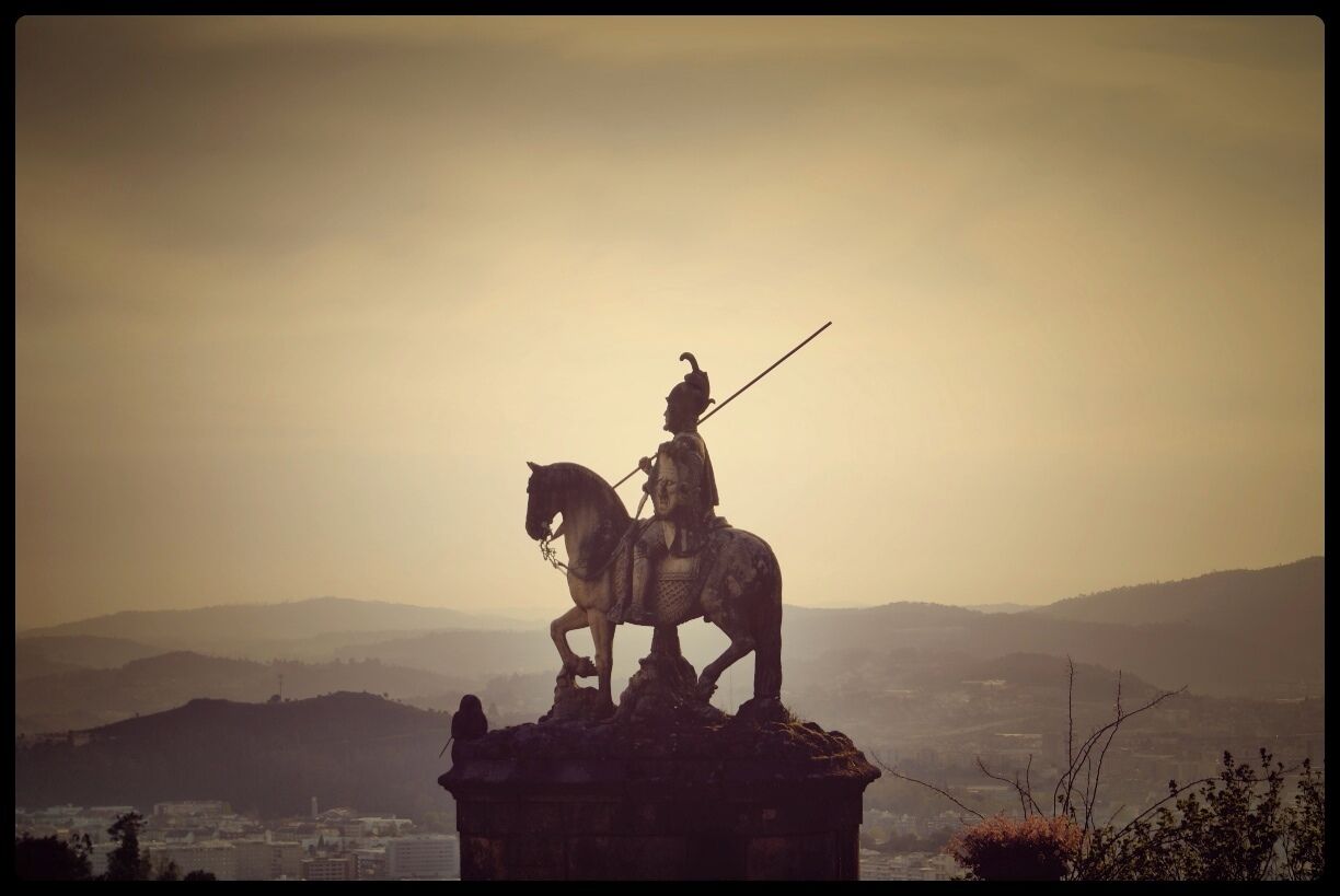 Una estatua de una persona a caballo con vista a un paisaje urbano y colinas lejanas.