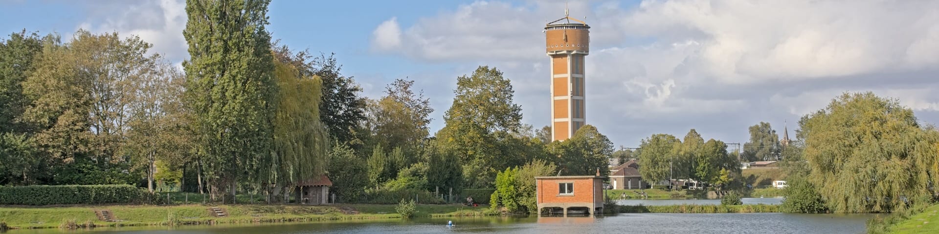Fish pond and brickt stone watertower in a park in the city of Melle, Flanders, Belgium