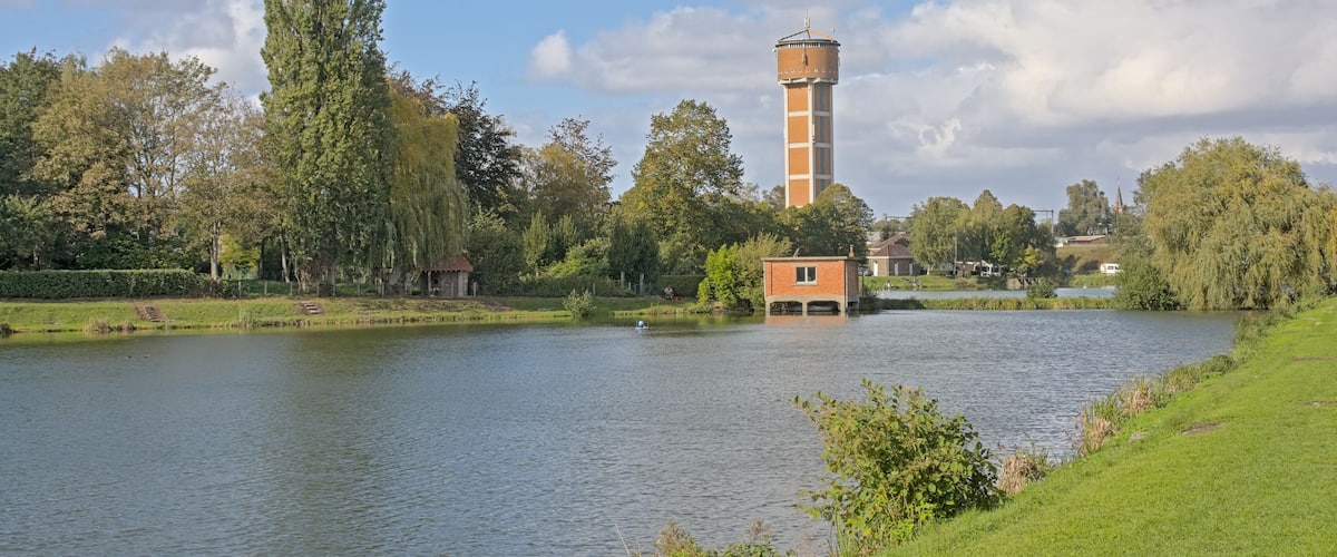 A calm lake with a tower and a small building on the shore.