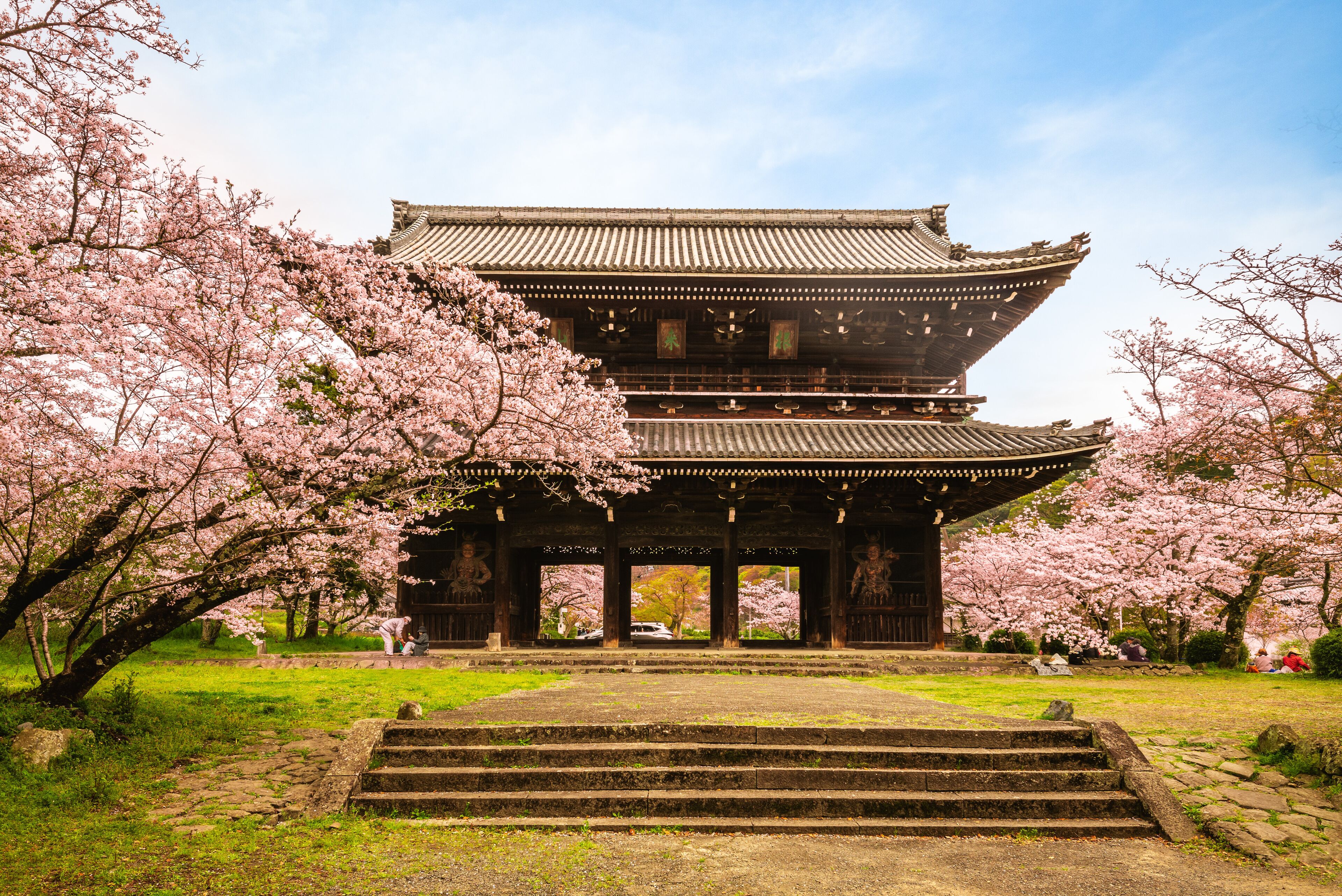 A traditional Japanese building with a multi-tiered roof, surrounded by cherry blossom trees.