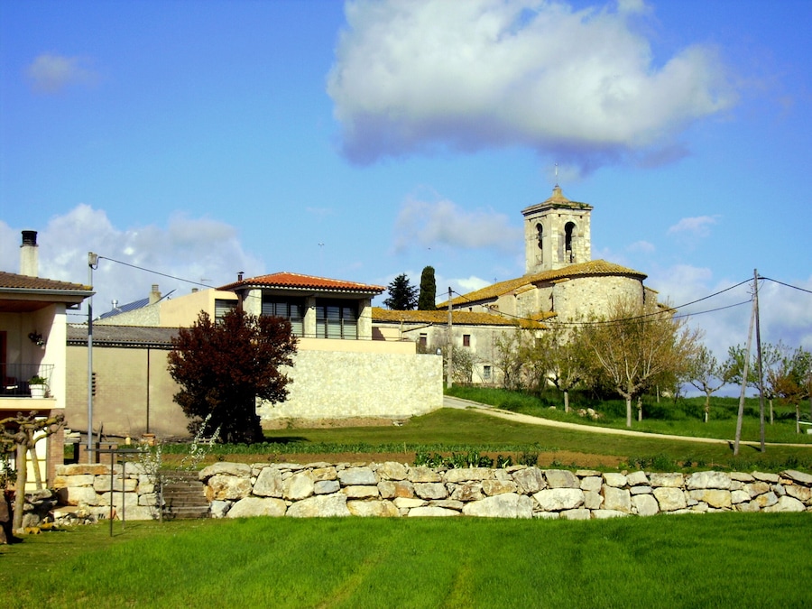 A stone church with a bell tower, surrounded by a stone wall and a grassy area.