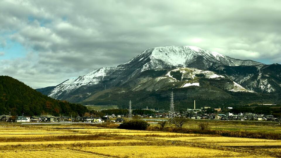 A snow-capped mountain, a town with houses, and fields.