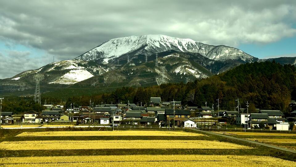 A town with traditional houses in front of a snow-capped mountain.
