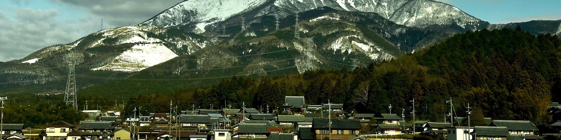 Eine Stadt mit traditionellen Häusern vor einem schneebedeckten Berg.