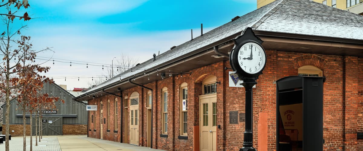 A brick building with a clock, a bench, and a sign for 'Firesides.'