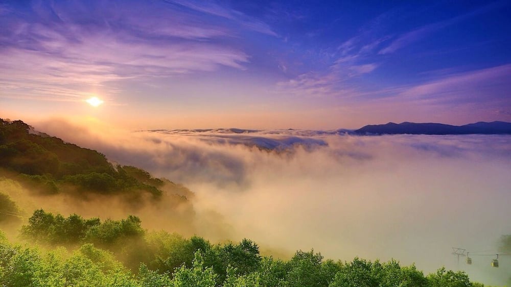 A sunrise over a mountainous landscape with a valley shrouded in mist.