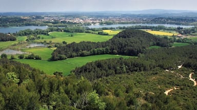 Un paisaje verde exuberante con un lago, colinas boscosas y un pueblo lejano.
