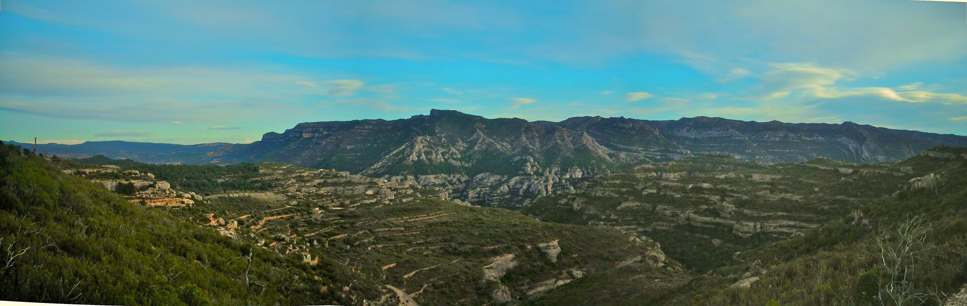 A mountainous landscape with terraced fields and a prominent rocky peak.