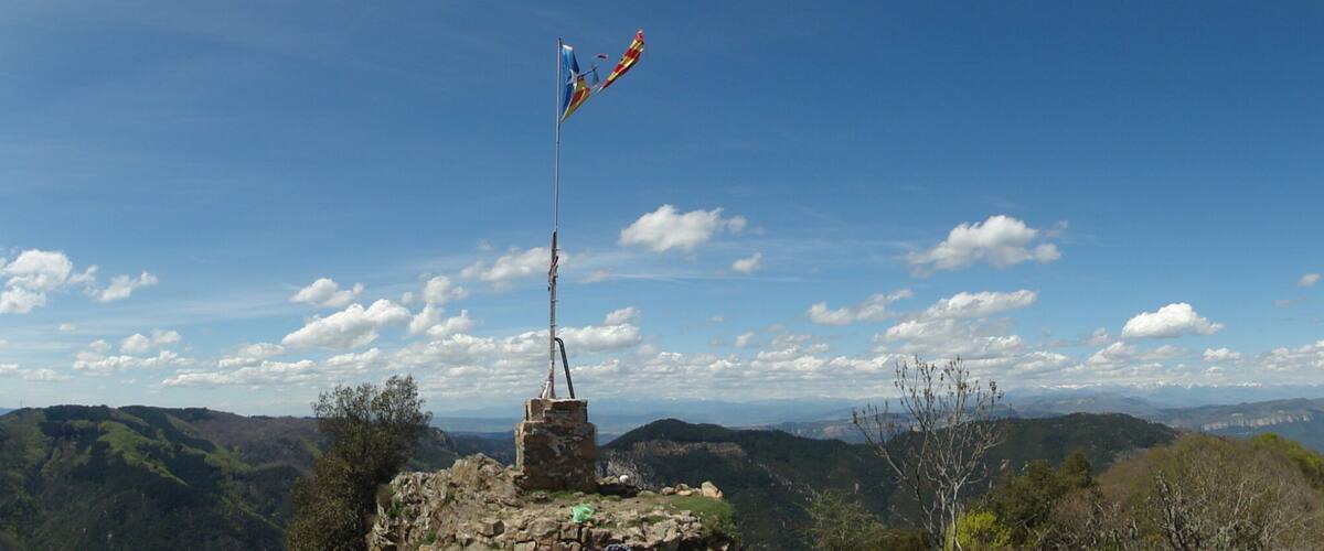 A mountainous landscape with a flagpole and a clear blue sky.