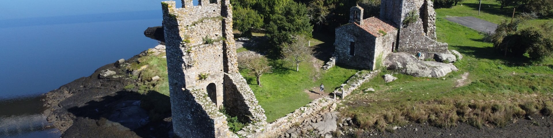 A coastal castle ruins with a bridge in the background.