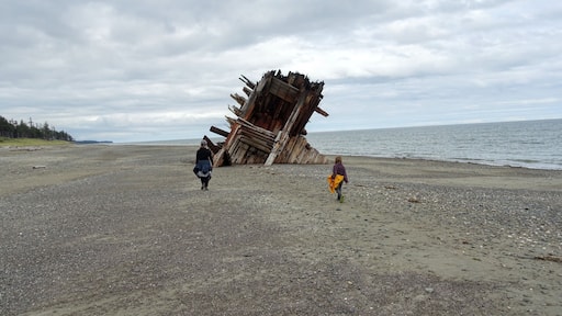 A mom and daughter exploring the Pesuta Shipwreck site, a popular tourist attraction outside Tlell, in Naikoon Provincial Park, Haida Gwaii, Canada. The wooden ship is on a sandy beach by the ocean