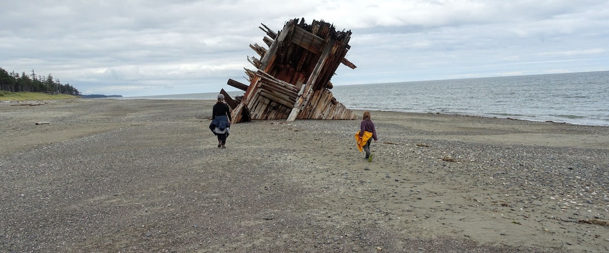 A beach with a large, tilted structure made of wooden beams.