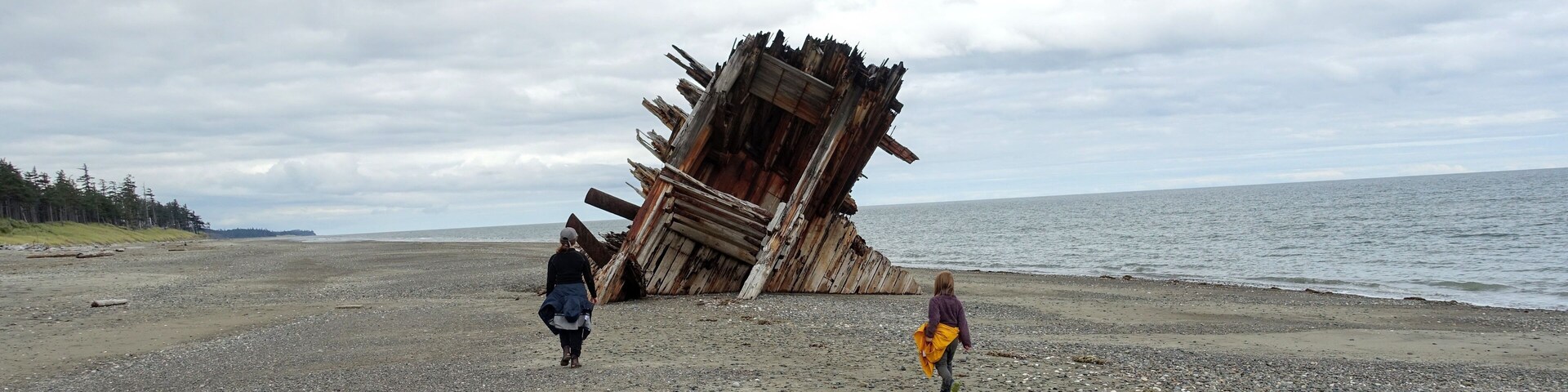 A beach with a large, tilted structure made of wooden beams.