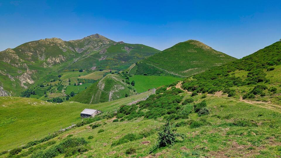 A mountainous landscape with a small house on a slope.