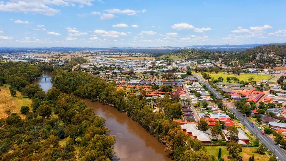 A river flowing through a town with houses and greenery.