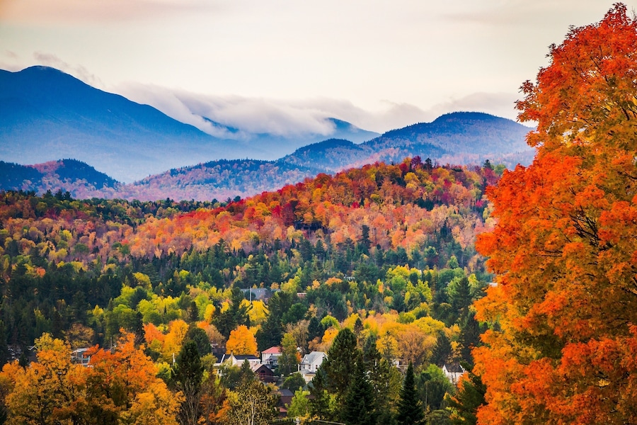 A mountainous landscape with autumn foliage, houses, and a river.