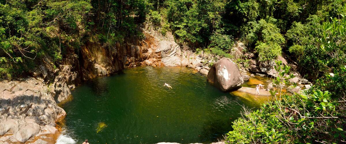 A natural pool surrounded by rocky terrain and dense forest.