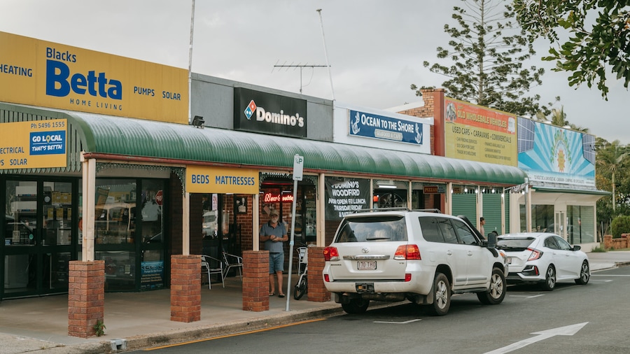 Une rue où se trouvent divers commerces, notamment un restaurant Domino's, un restaurant de fruits de mer et un magasin de panneaux solaires.