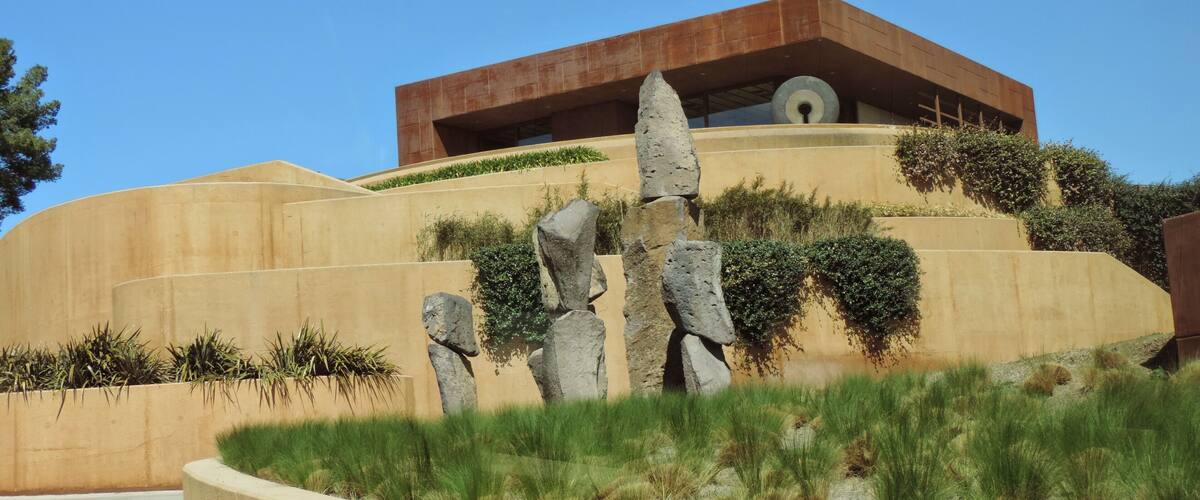 A modern building with a unique rock formation in front.