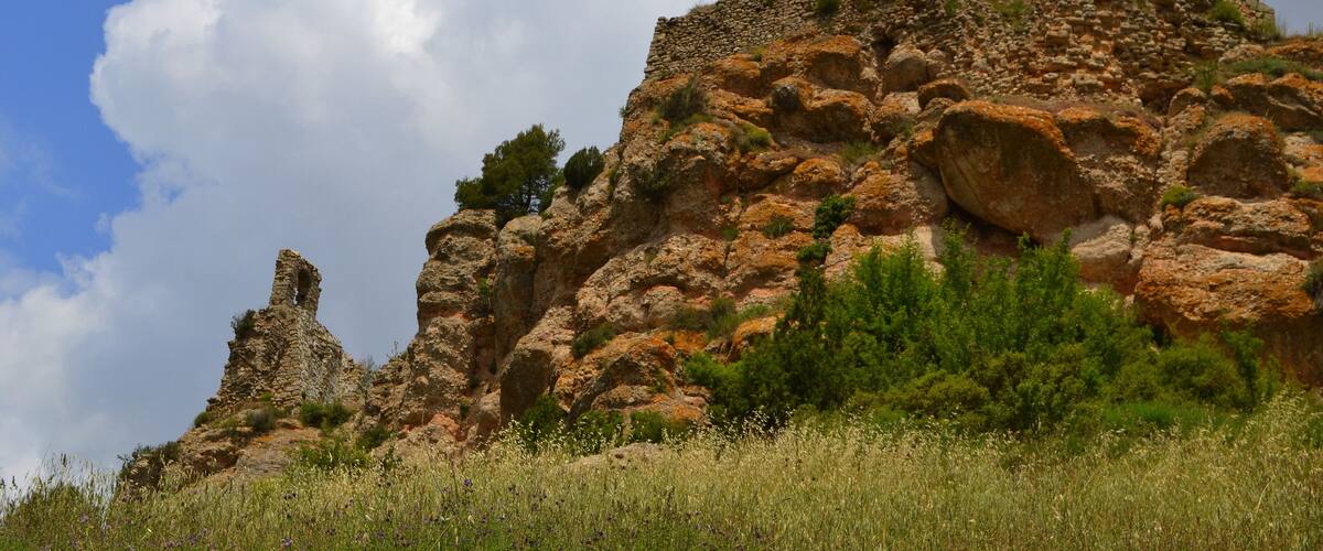 A rocky cliff with ancient ruins and a clear sky.