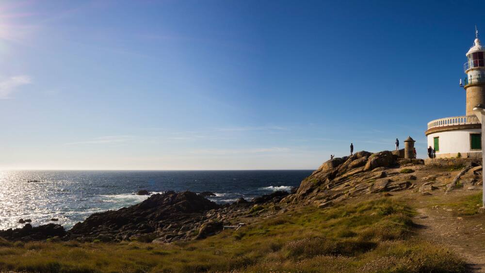 A coastal landscape with a lighthouse, rocky terrain, and the ocean.