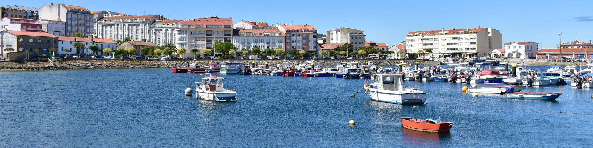 Harbour and coastal village with galician fishing vessels, rowboats and sailing boats at famous Rias Baixas in Galicia Region. Portosin, Coruña, Spain.