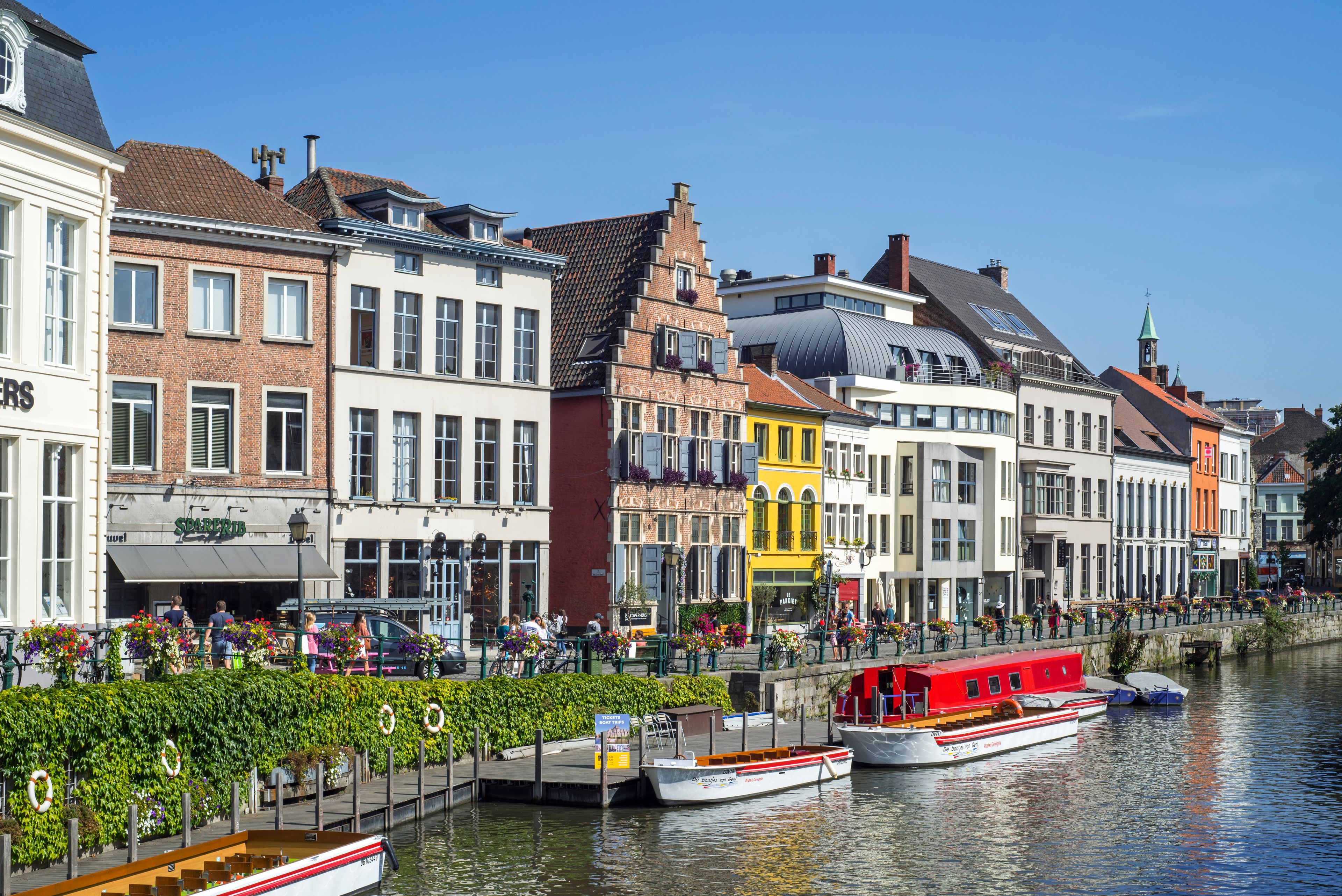 Een gracht met boten, een rij kleurrijke gebouwen en een helderblauwe lucht.