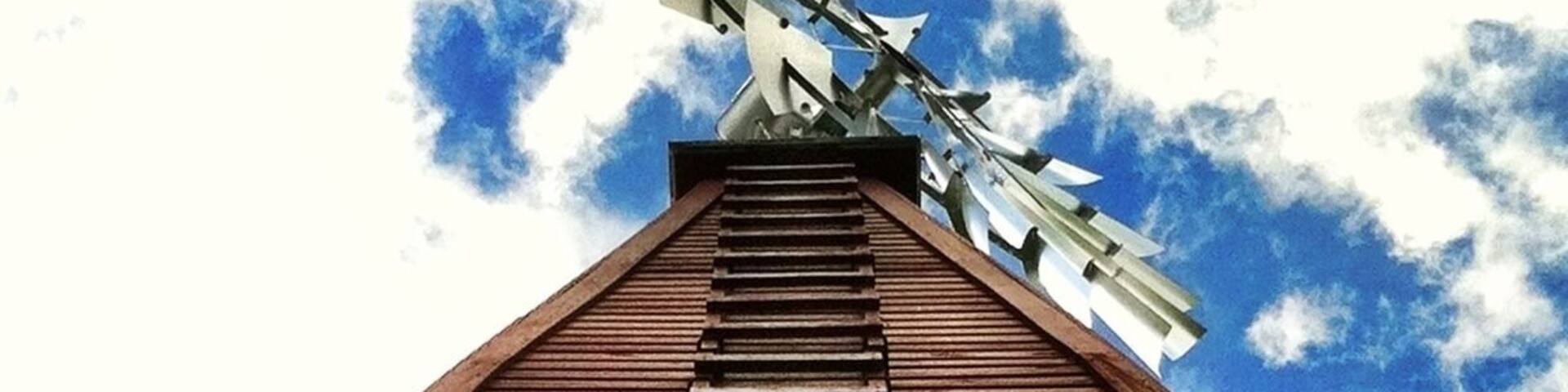 A wooden staircase leading up to a windmill against a partly cloudy sky.